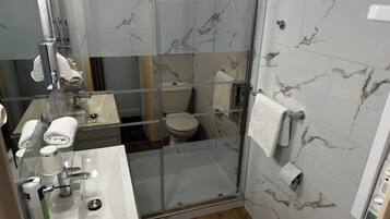 Ein modernes Badezimmer mit einer Duschkabine, einem Waschbecken mit Seifenspender und einer Toilette.
