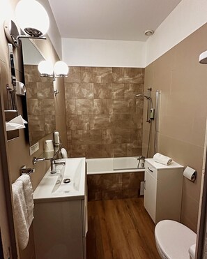 A modern bathroom with a bathtub, toilet, and sink. - Logis Hôtel le Passiflore (Chateaubernard)