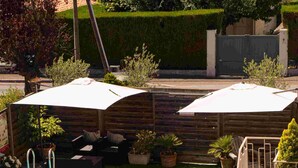 A swimming pool with a wooden deck, a covered seating area, and a well-maintained lawn. - Logis Hôtel le Passiflore (Chateaubernard)