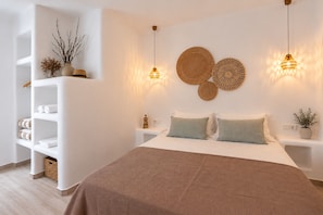 Un dormitorio moderno con una cama grande, dos mesitas de noche, una lámpara de pared y un adorno en la pared.