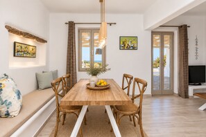 A dining area with a wooden table, chairs, and a vase with lemons. - Villa Rocabella – Just 100m from Glyfada Beach (Naxos)