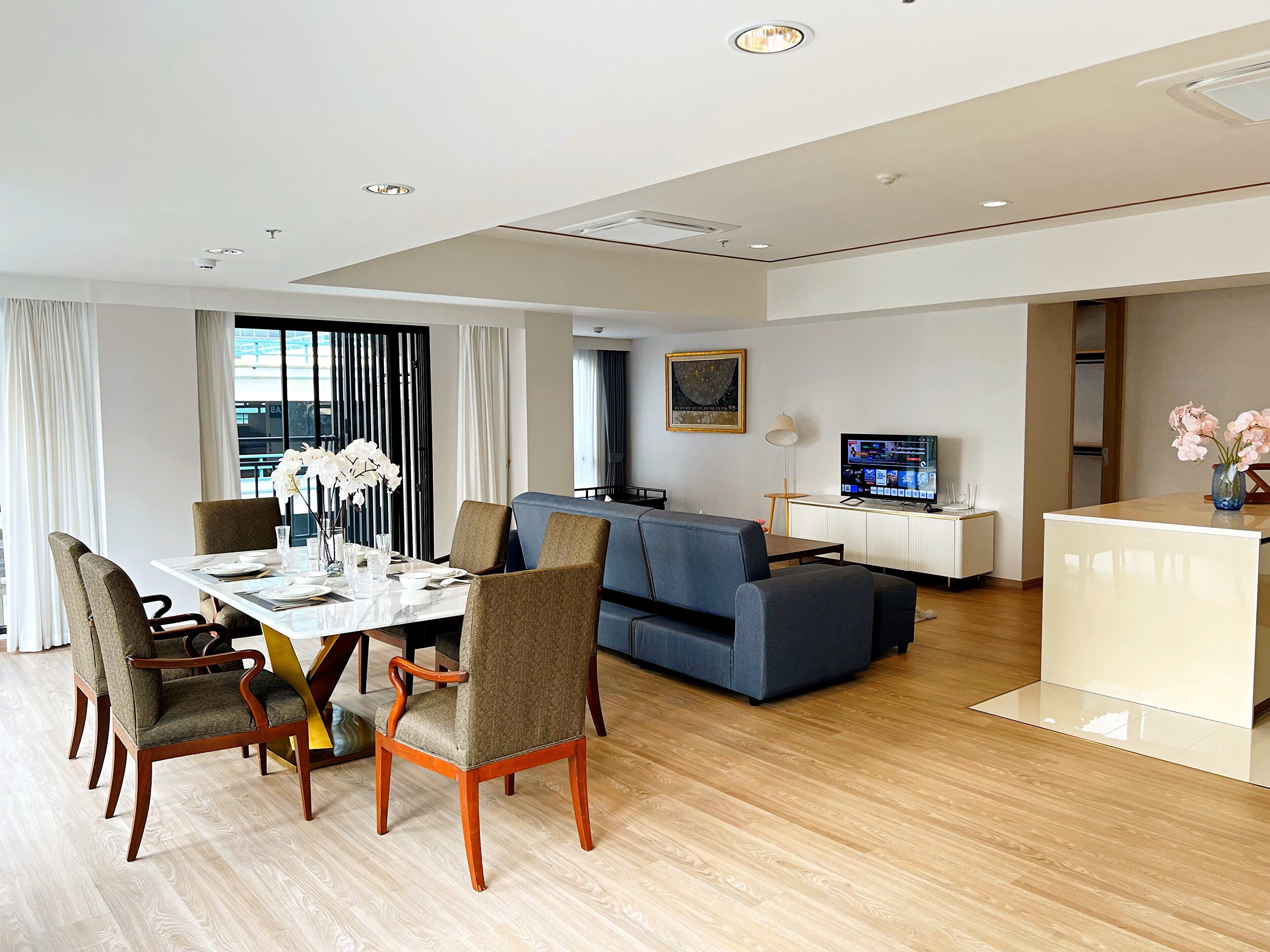 Une chambre d’hôtel moderne équipée d’un coin repas, d’un canapé, d’une télévision et d’un bureau.