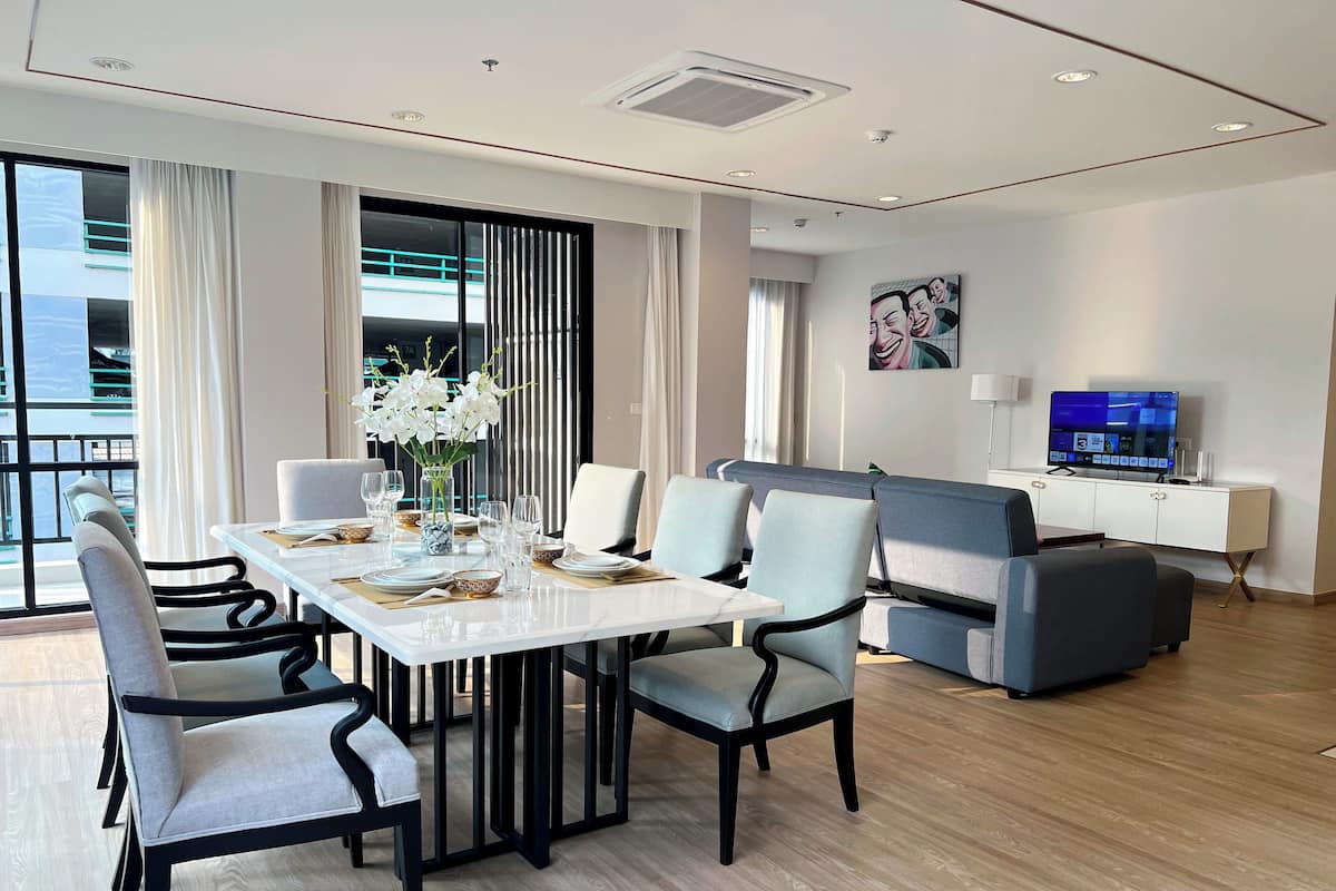 A modern hotel room with a dining area, a sofa, and a TV.