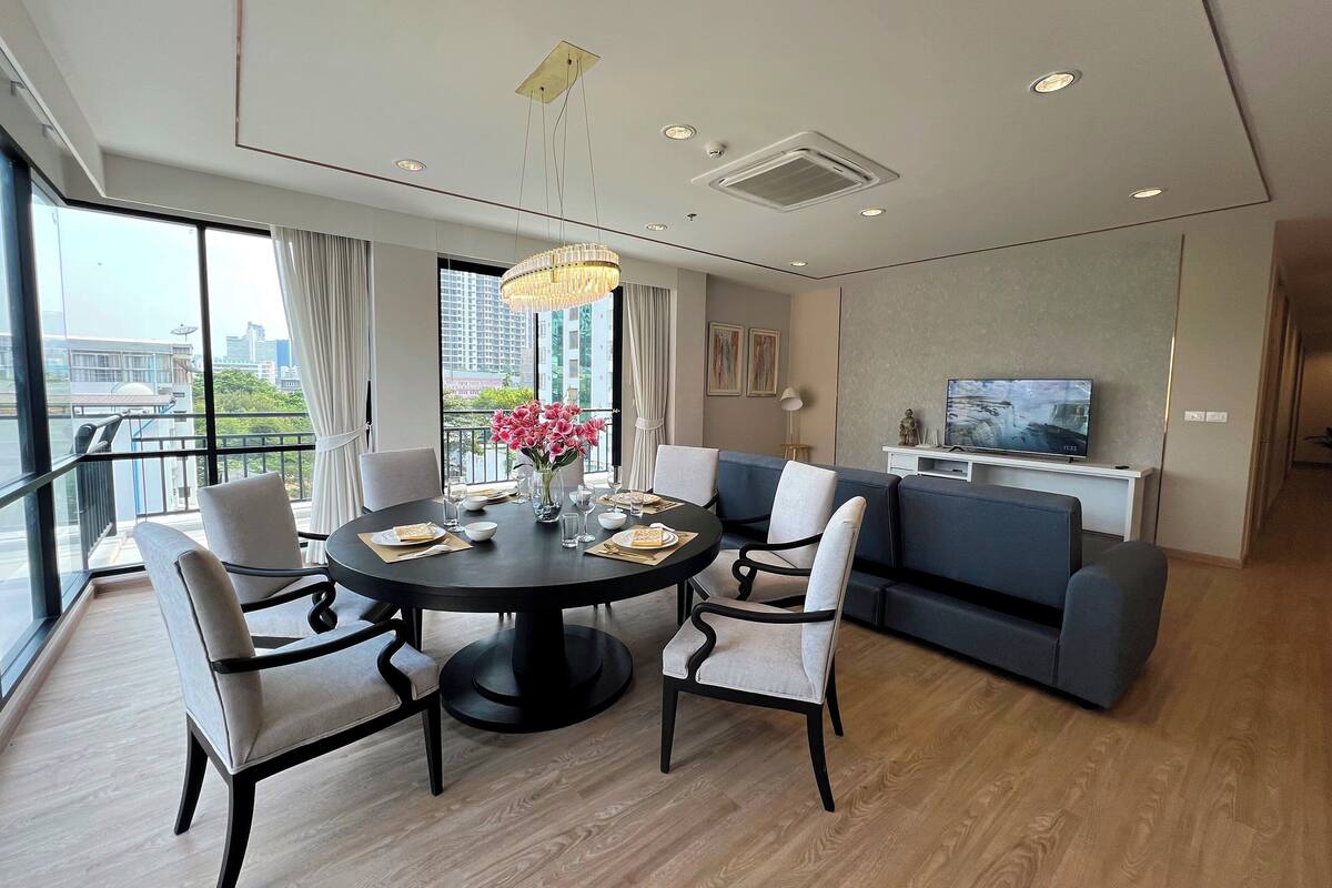 A modern dining area with a round table, chairs, and a vase of flowers.