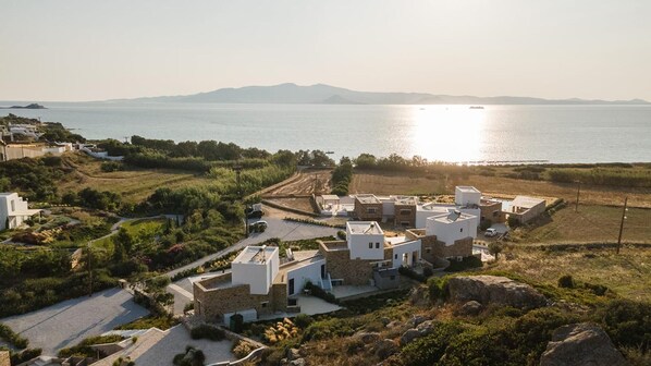 Un pueblo costero con edificios blancos, una carretera pavimentada y vistas al mar y las montañas.