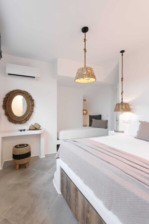 Une chambre à coucher comprenant un lit, des tables de chevet, un miroir et un luminaire suspendu.