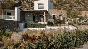 A modern house with a stone exterior, a flat roof, and a patio with outdoor furniture. - Villa Andalusia, Orkos Naxos (Naxos)