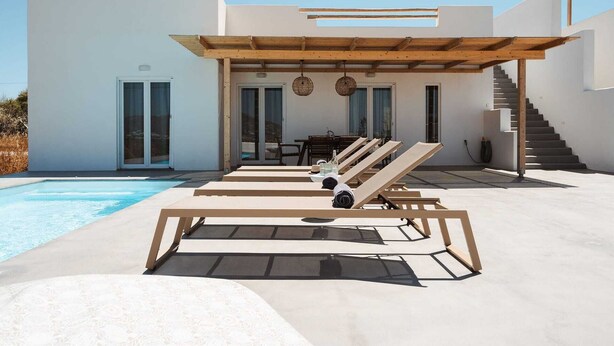 Ein moderner Poolbereich im Freien mit Liegestühlen, einer überdachten Sitzgelegenheit und einer Treppe, die zu einer erhöhten Ebene führt.