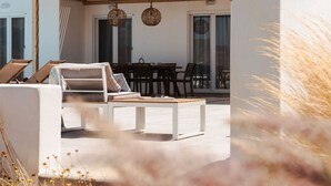 Ein moderner Außenbereich mit einer weißen Couch, einem Holztisch und einer Pergola darüber.