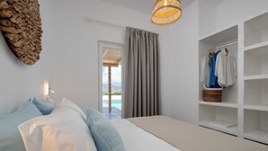 Ein Schlafzimmer mit Bett, Kleiderschrank, einem Fenster mit Vorhängen und Blick auf einen Pool.
