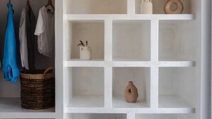 Ein weißes Regal mit mehreren Fächern, in einigen befinden sich dekorative Gegenstände wie eine Vase und eine Holzskulptur.