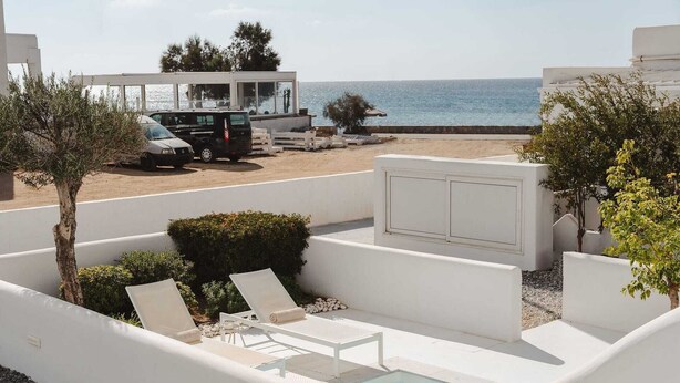 Un espace piscine avec des chaises longues, une petite piscine et une vue sur la plage et la mer.