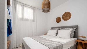 Une chambre à coucher bien rangée, avec un lit, des tables de chevet et une armoire.