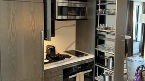 A modern kitchen with built-in appliances, a dining area with a table and chairs, and a view of the living area.