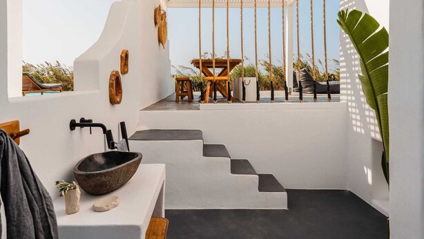 A modern bathroom with a stone sink, wooden accents, and a view of a pool and lounge chairs. - Villa Ama , Plaka Area , Naxos (Naxos)
