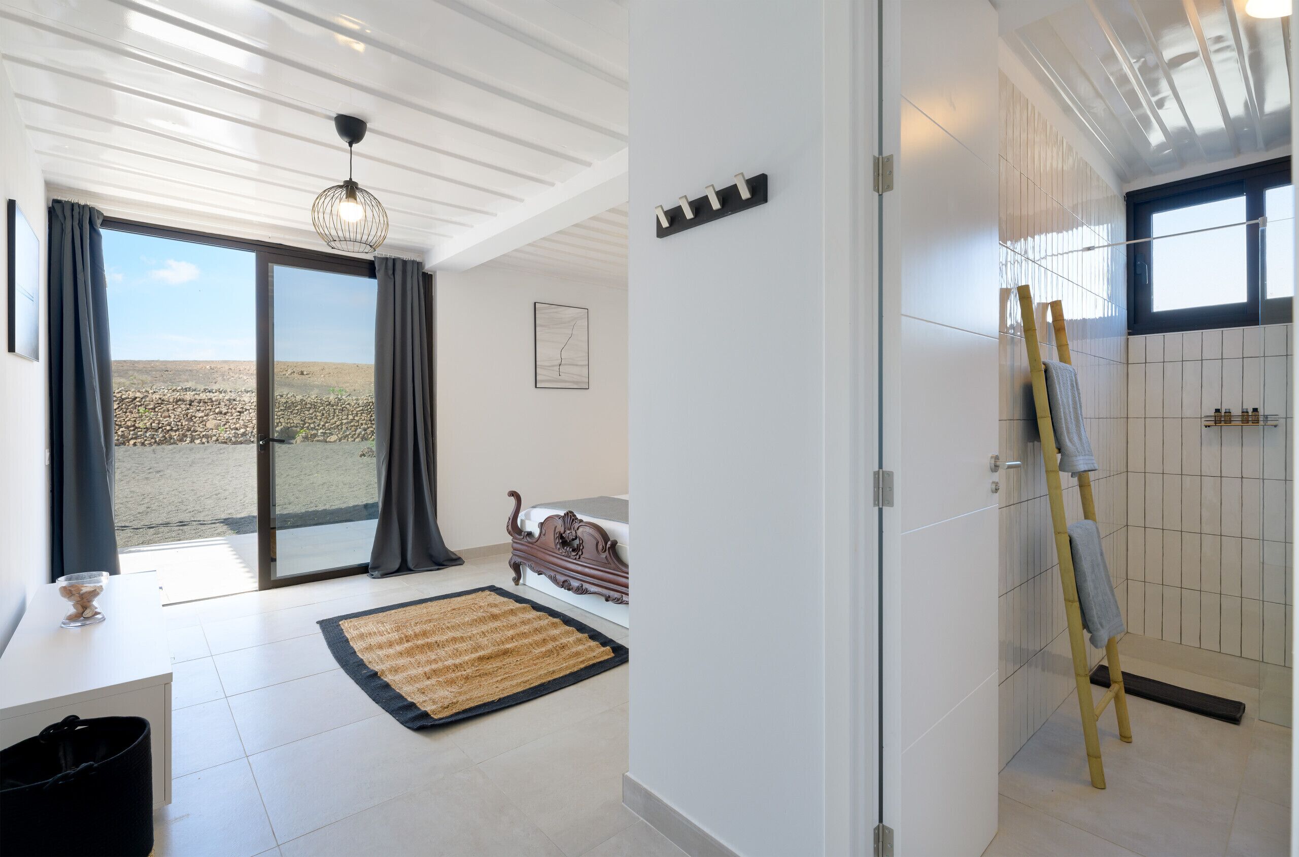 A modern bathroom with a shower, a towel rack, and a view of the outside.