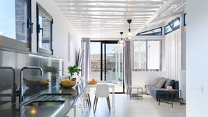 Eine moderne Küche mit einer Spüle aus Edelstahl, einem Essbereich mit weißem Tisch und Stühlen sowie einem Sofa und einem Beistelltisch.