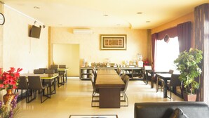A hotel dining area with a long table, multiple chairs, a coffee station, and a potted plant. - Collection O R.Sukamto Near Palembang Trade Center Mall (Palembang)