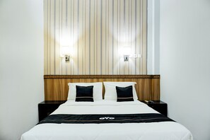 A hotel room with a bed, two bedside tables, a headboard with vertical stripes, and two wall-mounted lights. - Collection O R.Sukamto Near Palembang Trade Center Mall (Palembang)