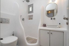 Un bagno moderno con un lavandino bianco, un water, una doccia e uno specchio.