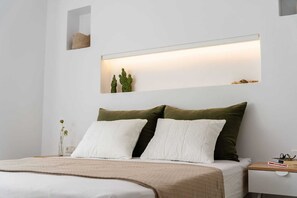 Una camera da letto moderna con un letto, cuscini, un comodino e una mensola a parete con oggetti decorativi.