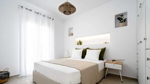 A modern bedroom with a large bed, a bedside table, a small bedside lamp, and a window with curtains.