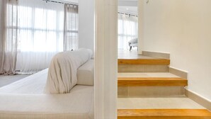 A modern interior with a sofa bed, wooden stairs, and sheer curtains. - Martinez in Llafranc (Palafrugell)