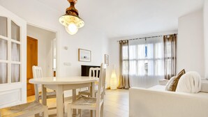 A modern living room with a white sofa, a dining table with chairs, a fireplace, and large windows with curtains. - Martinez in Llafranc (Palafrugell)