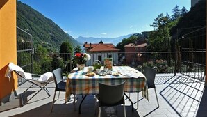 Une terrasse avec une table dressée pour le repas, des chaises et un pot de fleurs.
