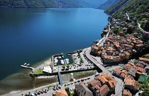 Vista aérea de un pueblo a orillas del lago, con un puerto deportivo, calles estrechas y edificios tradicionales.