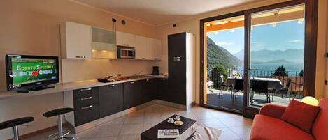 Une cuisine moderne équipée d’un téléviseur, de tabourets de bar et d’un coin repas offrant une vue sur les montagnes.
