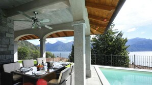 Un espacio para comer al aire libre con piscina y vistas a la montaña.