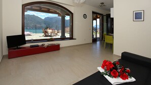 Un salon doté d’une grande fenêtre, d’un téléviseur à écran plat, d’un meuble de rangement rouge et d’un canapé noir agrémenté d’un arrangement floral.