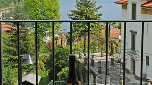 A balcony with a bottle, glasses, and strawberries. - Residence Eden Magnolia 15 (Argegno)