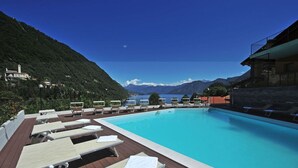 A pool area with lounge chairs and a view of mountains and a lake. - Residence Eden Magnolia 15 (Argegno)