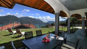 An outdoor patio with a table set for two, overlooking a mountainous landscape. - Villa Aurelia in Plesio (Plesio)