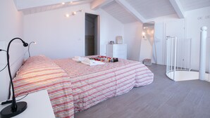 A bedroom with a bed, a desk with a lamp, a dresser, a mirror, and a shower area. - Casa Laura Apt 6 in Il Piazzo (Plesio)