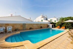 A swimming pool with a tiled edge, surrounded by stone tiles and a few lounge chairs. - Villa Fina in Ciutadella de Menorca (Ciutadella de Menorca)