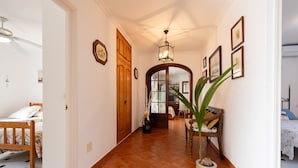 Un couloir avec une porte en bois, une plante et des tableaux encadrés accrochés au mur.