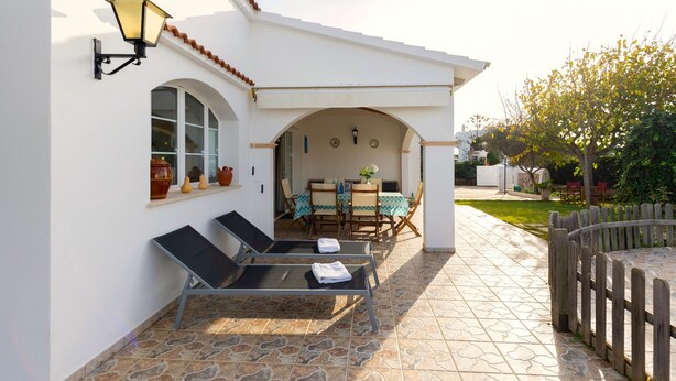 Une terrasse avec deux chaises longues, une table avec des chaises et une clôture en bois.