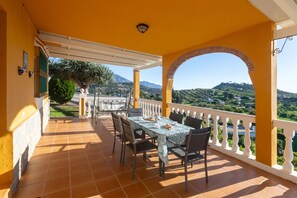 Un portico coperto con tavolo e sedie, vista su dolci colline e una montagna all'orizzonte.