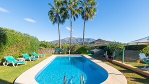 A rectangular swimming pool with a curved edge, surrounded by a grassy area with green lounge chairs. - El Descanso in Mijas (Mijas)