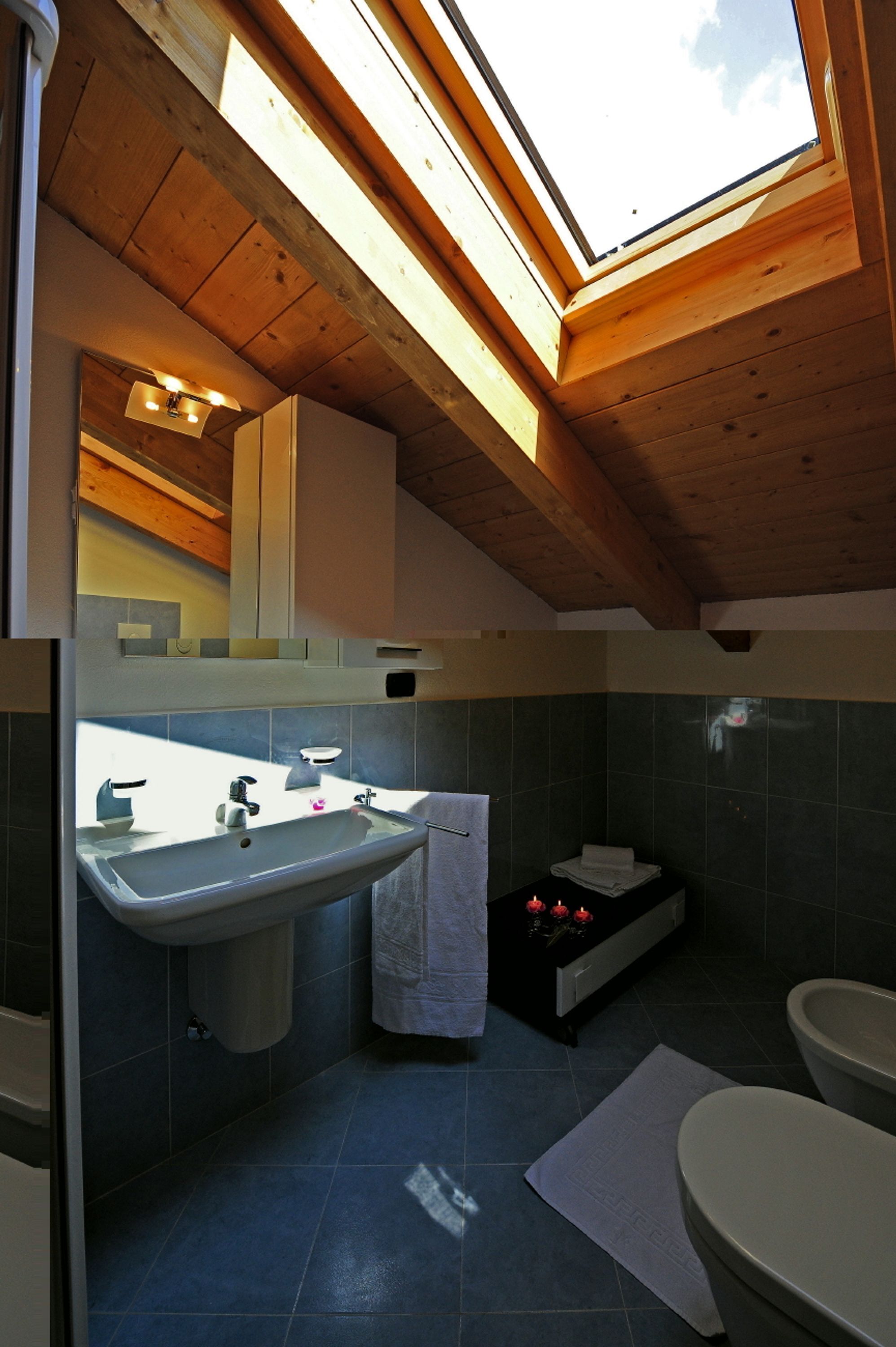 A bathroom with a skylight, a sink, a toilet, and a bathtub.
