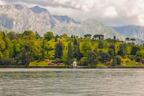 A lakeside view with a small white gazebo surrounded by lush greenery and mountains in the background. - Casa Laura Apt 3 in Il Piazzo (Menaggio)