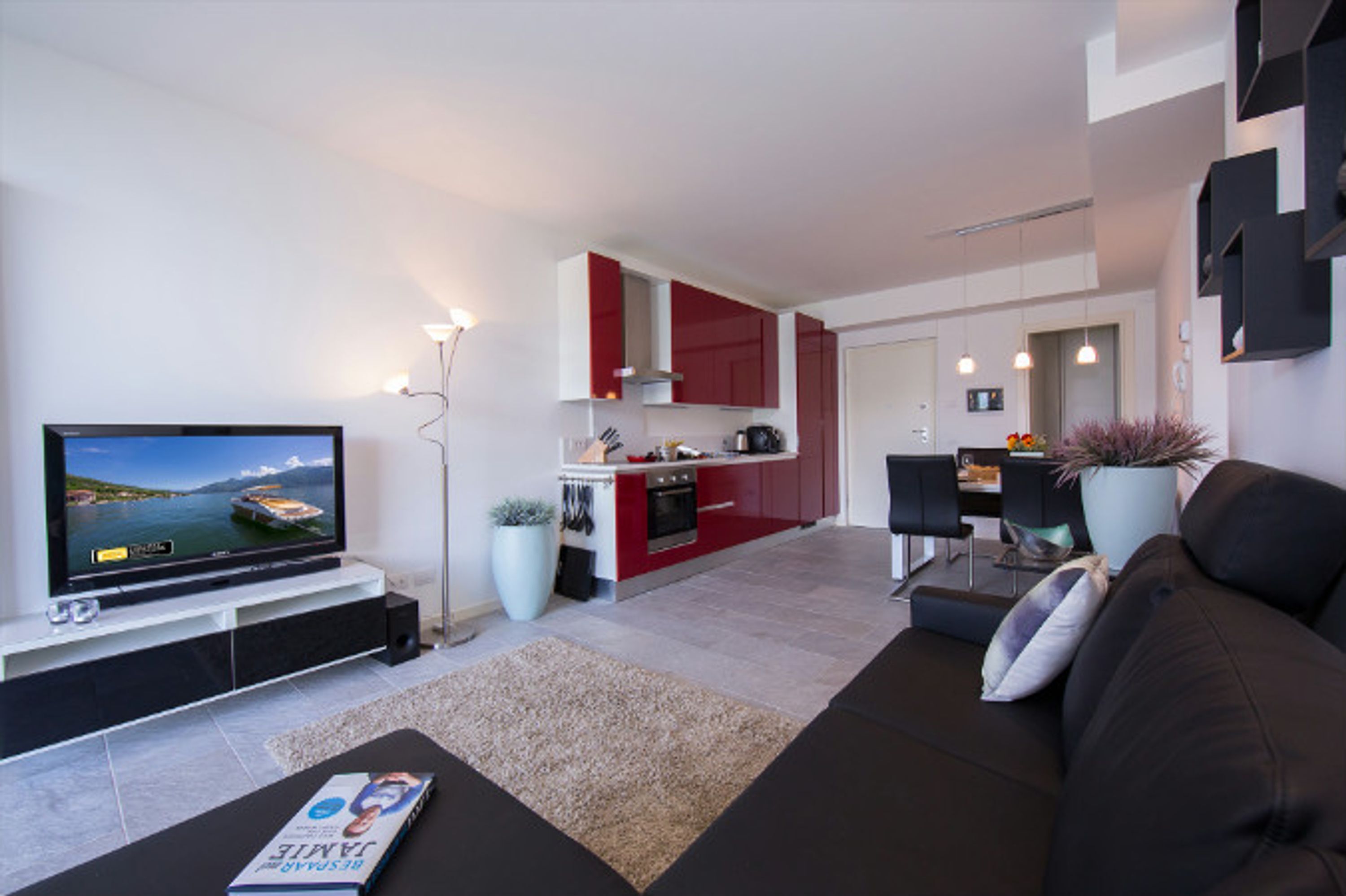 Een moderne woonkamer met een flatscreen televisie, een donkere bank en een salontafel.