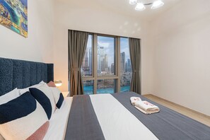 Ein Hotelzimmer mit einem großen Bett, Blick auf eine Stadtansicht und einem Gemälde an der Wand.