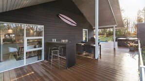 A modern outdoor deck with a pool, bar area, and seating. - Beautiful home in Glesborg (Glesborg)