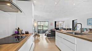 A modern kitchen with a central island, a dining area with a sofa, and a view of the outdoors. - Beautiful home in Glesborg (Glesborg)