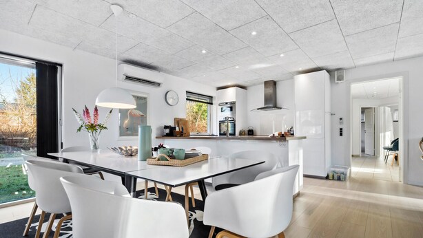 A modern kitchen with a central island, white chairs, and a view of the outdoors. - Beautiful home in Glesborg (Glesborg)