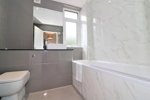 Ein modernes Badezimmer mit Toilette, Waschbecken und Badewanne.
